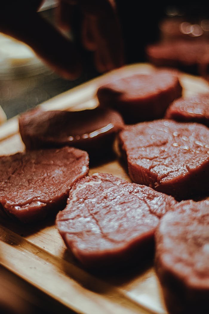 Fresh raw beef slices arranged on a wooden tray, ready for cooking.
